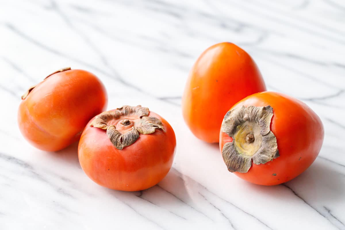 Comparing the shape of Fuyu persimmons (which are short and squat) to Hachiya persimmons (which are larger and oblong).