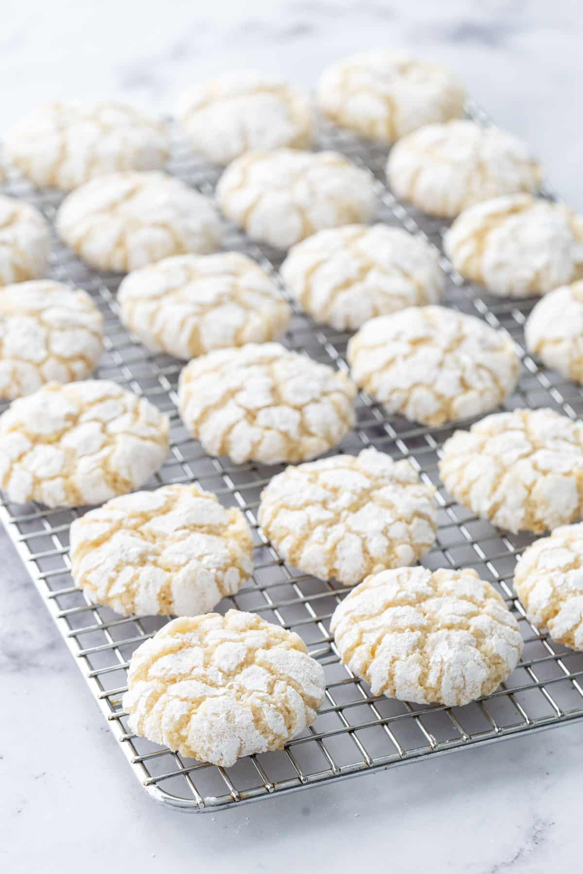 Rows of Chewy Lemon Almond Crinkle Cookies on a wire baking rack.