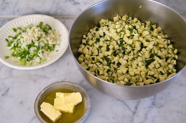 chopped zucchini, butter, olive oil, and onions to make zucchini butter in a kitchen