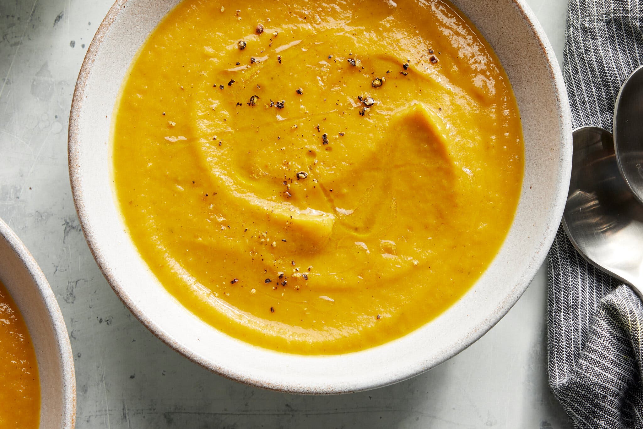A bowl of butternut squash soup is photographed from overhead.