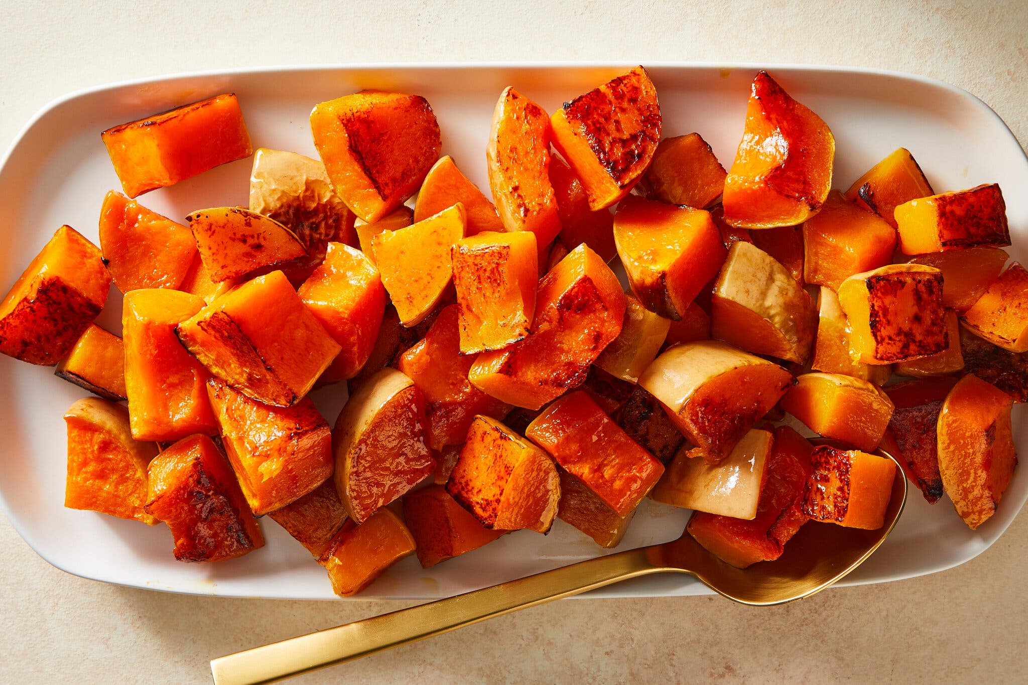 An overhead image of cubed roasted squash on a white platter.